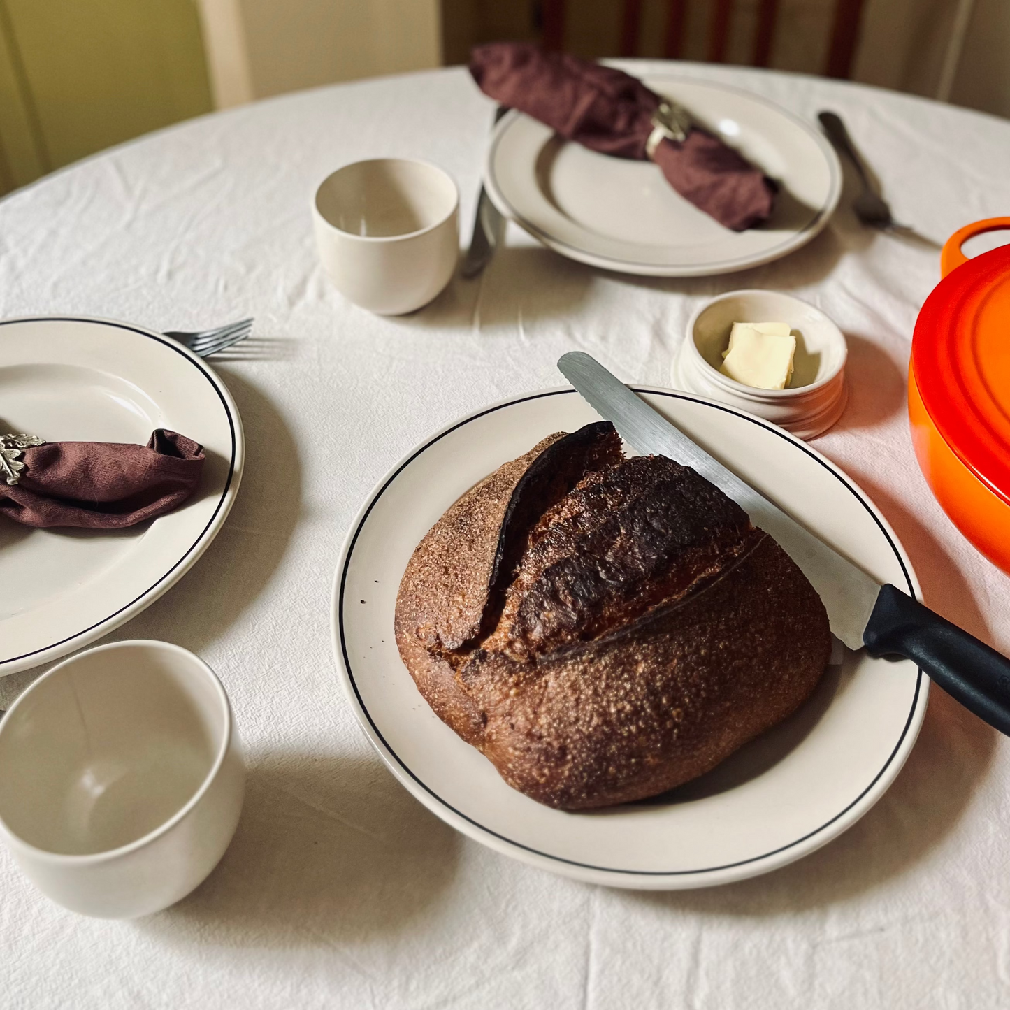 Dinner table setting with a large serving plate, cutlery, and tablecloth